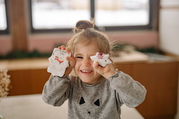 Girl In Gray Sweater Holding Cookies And Smiling