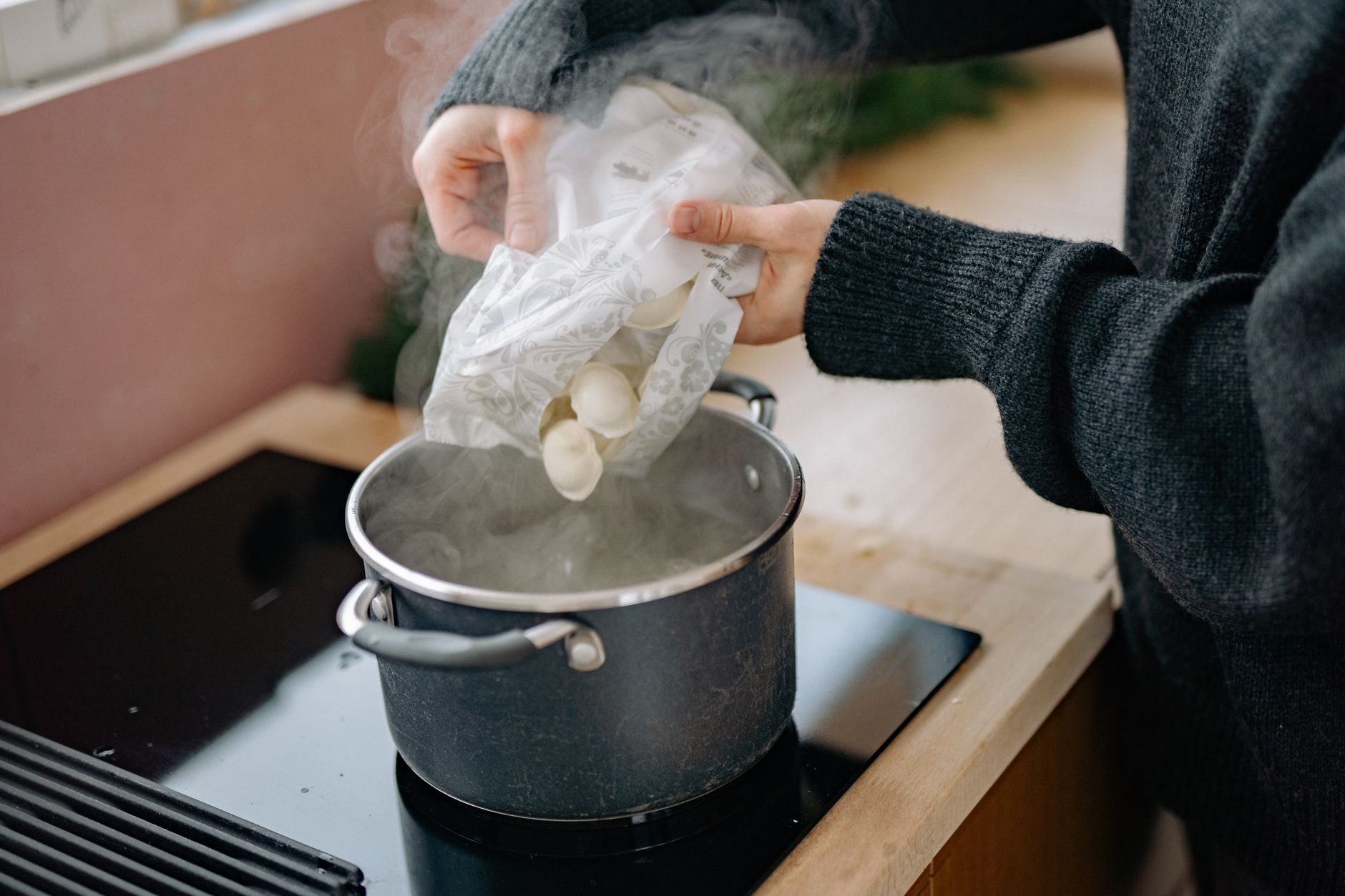 Hands lowering dumplings over a steaming pot, a reminder that steam is older than any showroom appliance.
