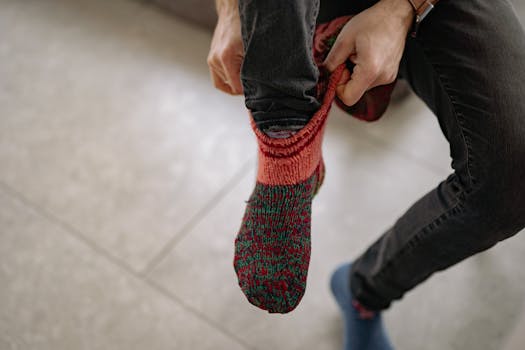 Man pulling on colorful knit socks, capturing warmth and coziness.