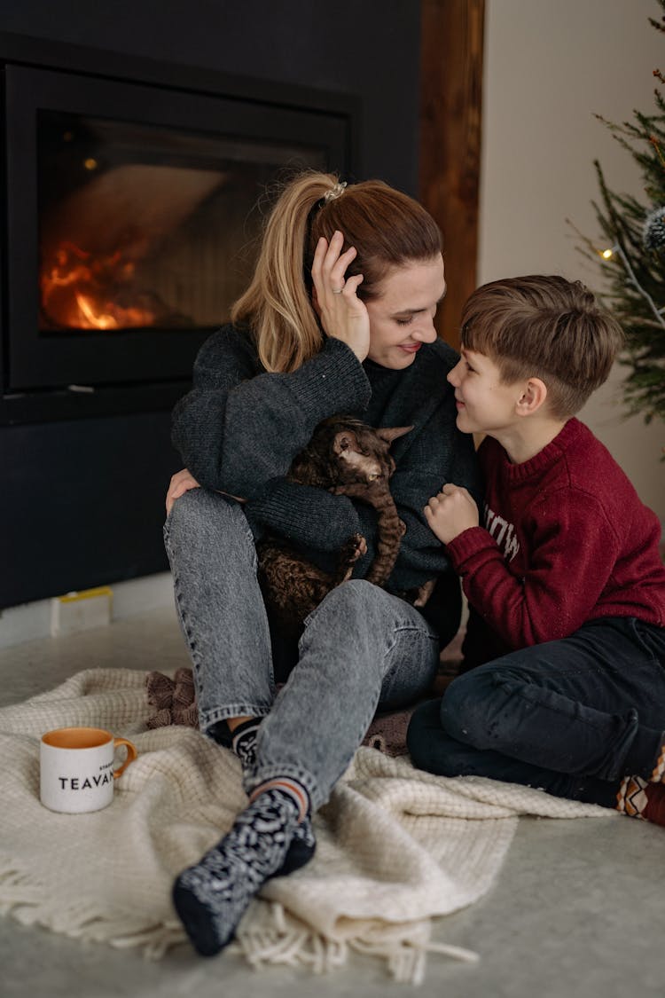 Mother And Son With A Cat By A Fireplace 