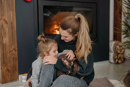 Free A Woman Sitting by the Fireplace With Her Daughter  Stock Photo