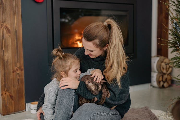 A Woman Sitting By The Fireplace With Her Daughter 