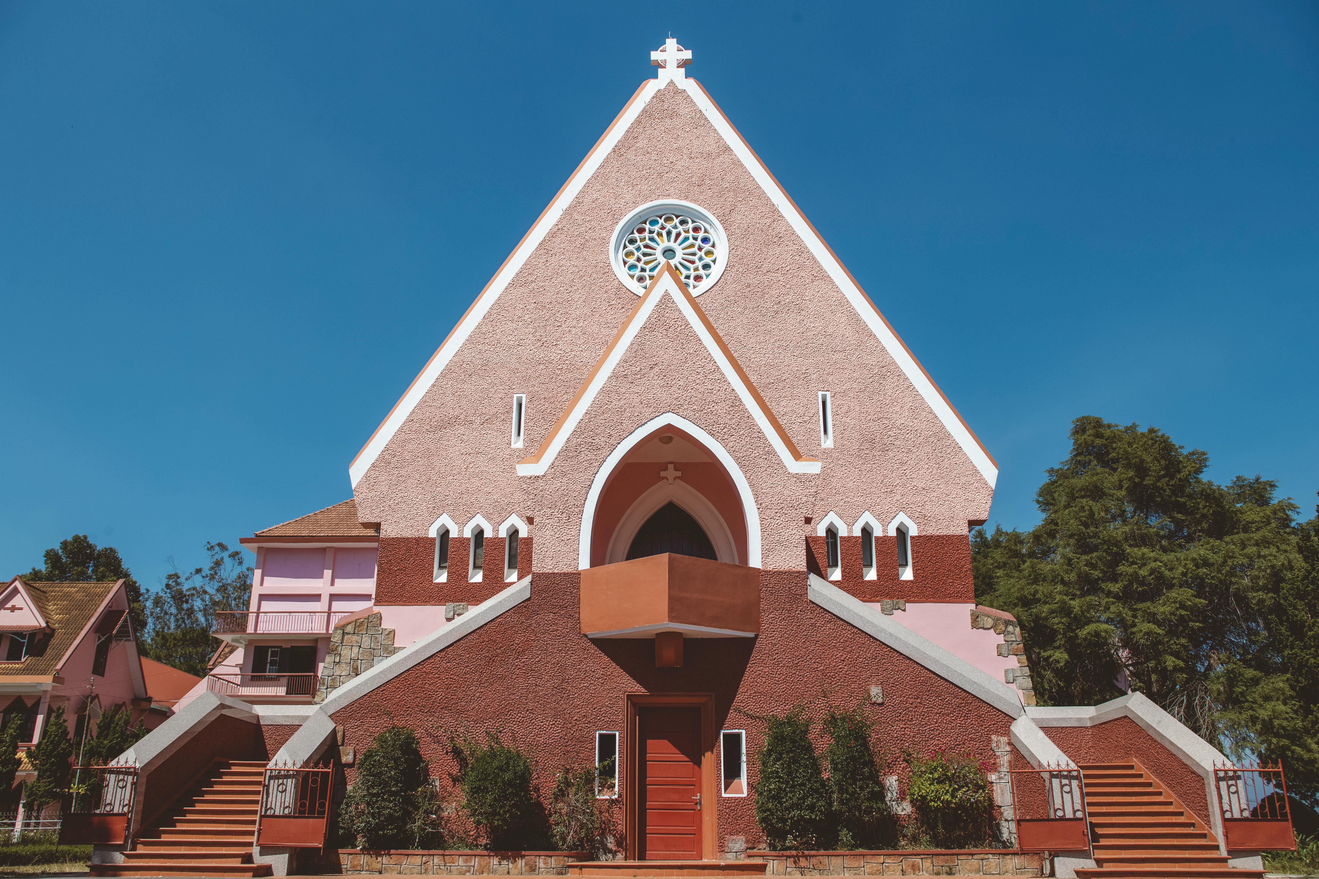 Traditional Domaine de Marie Church with pink facade in Dalat, Vietnam under a clear blue sky.