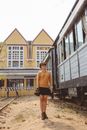 Woman in Brown Long Sleeve Shirt and Black Skirt Standing on Train Rail