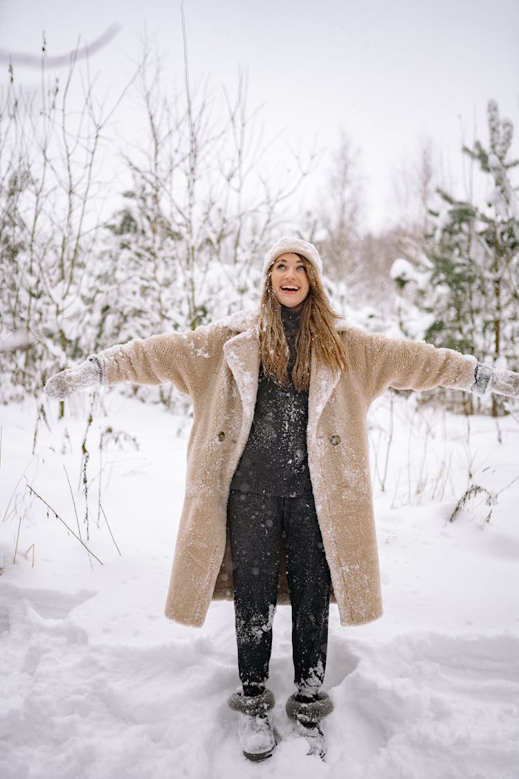 A Happy Woman Standing In The Snow With Arms Outstretched