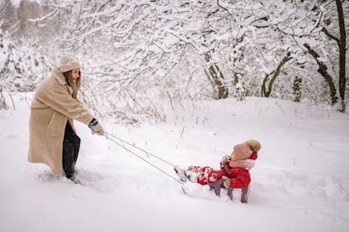 Woman Pulling a Kid on a Sled