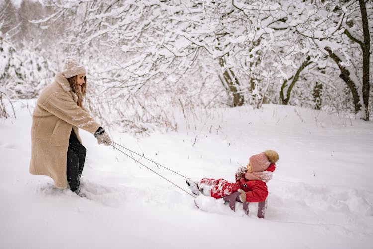 Woman Pulling A Kid On A Sled