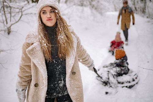 Free Family enjoying playful winter adventure outdoors, sledding through snowy forest trails in cozy attire. Stock Photo
