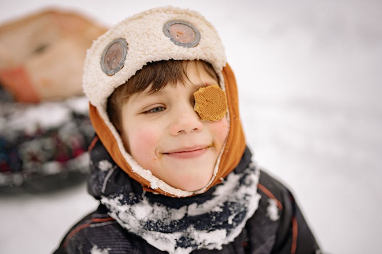 Portrait Of A Boy Wearing Winter Clothes With A Biscuit On His Eye