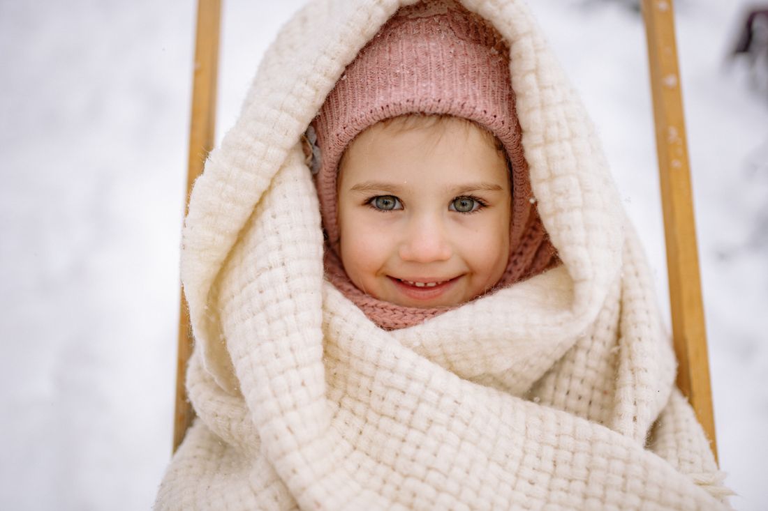 Young child wrapped in a warm blanket outdoors in the snow — photo by Yan Krukau on Pexels