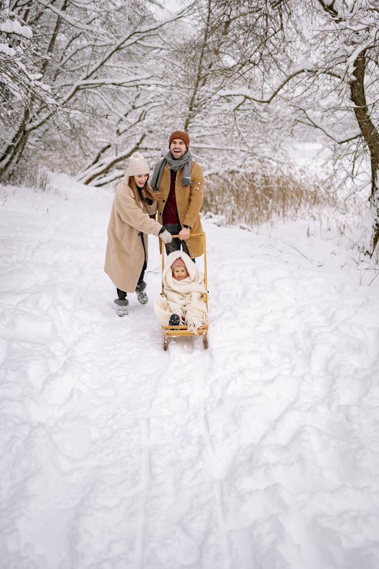 Couple Posing With Their Child On The Sled 