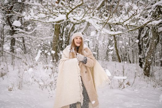 A cheerful woman laughing under snow-covered trees, embodying the winter spirit.