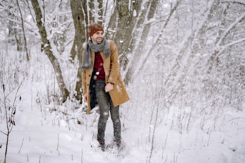 A Man Standing on the Snow Covered Ground with Trees