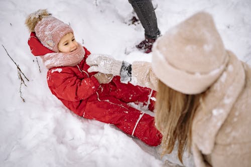 Free A Kid Wearing Winter Clothes Lying Down on Snowy Ground Stock Photo
