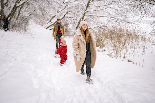 A Family in Winter Clothes Walking on a Snow-Covered Ground