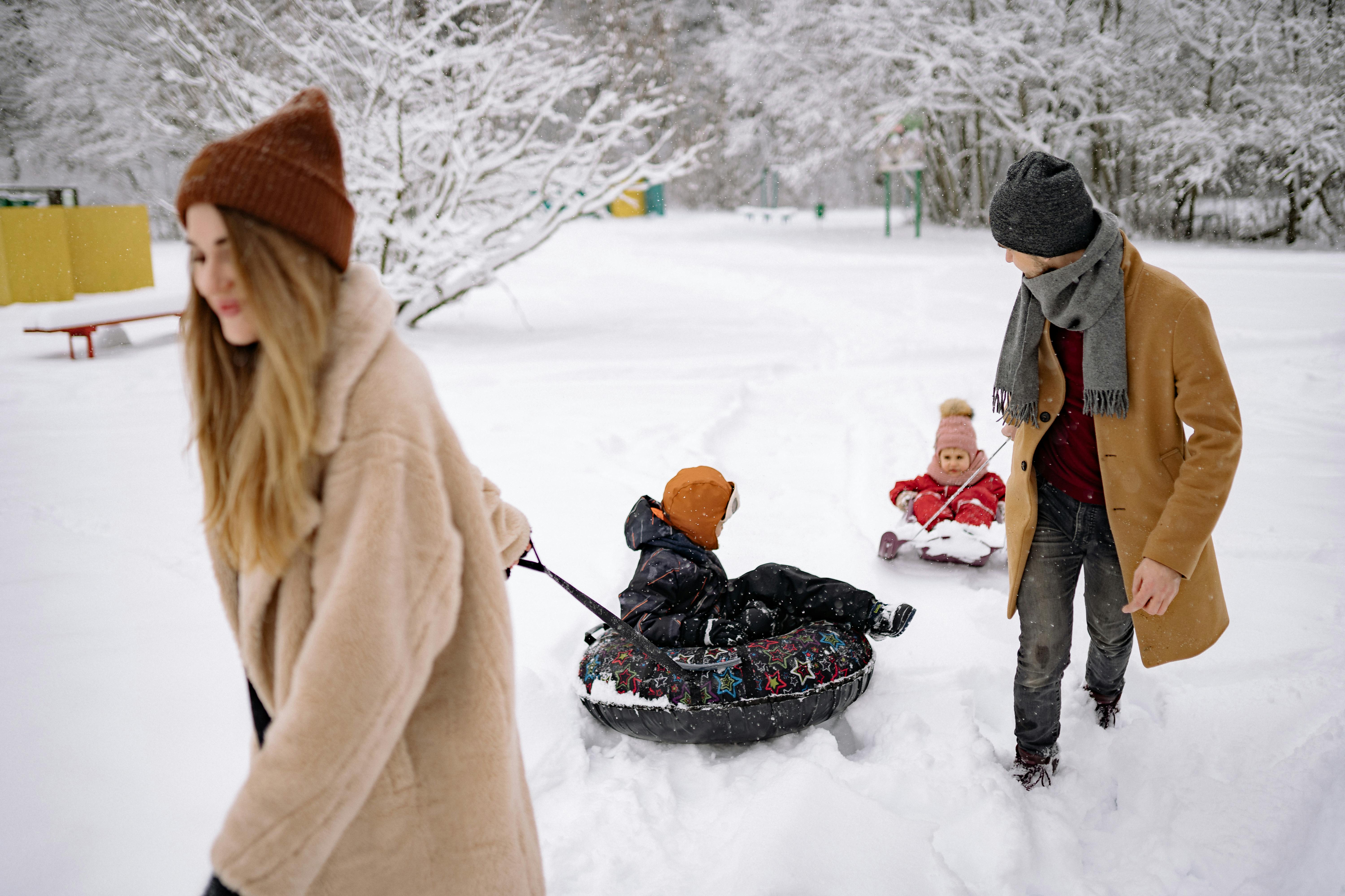 a couple pulling snow tubes on the snow with the kids