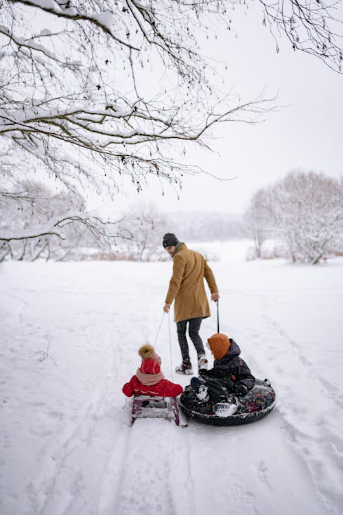 A Man Pulling a Sled and Snow Tube