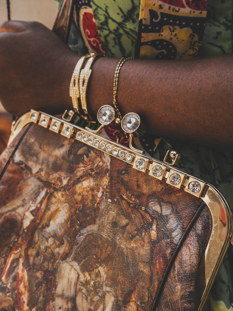 Person Carrying A Bag With Gold And Gemstone Details