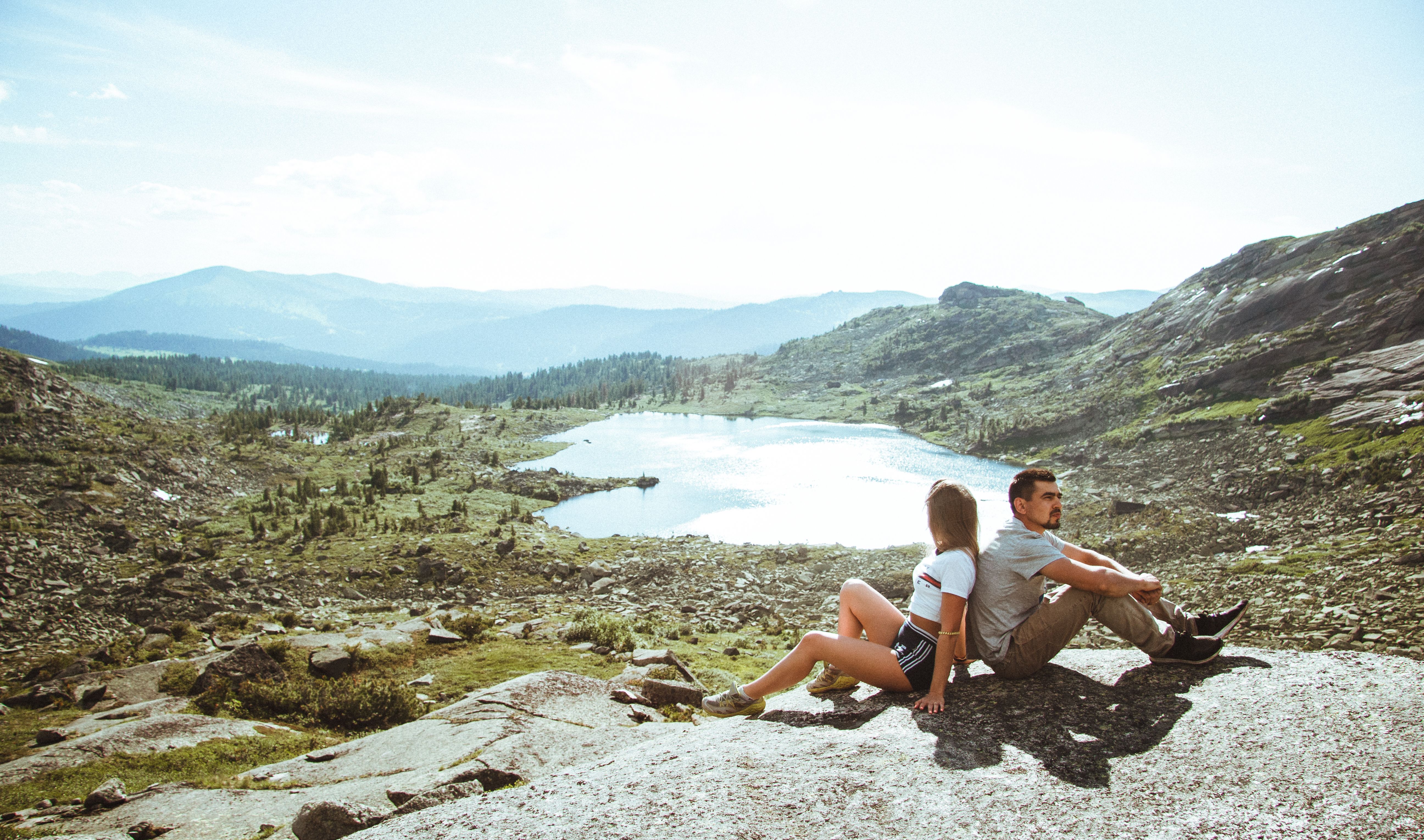 A couple sitting and enjoying a scenic view over a mountain lake.