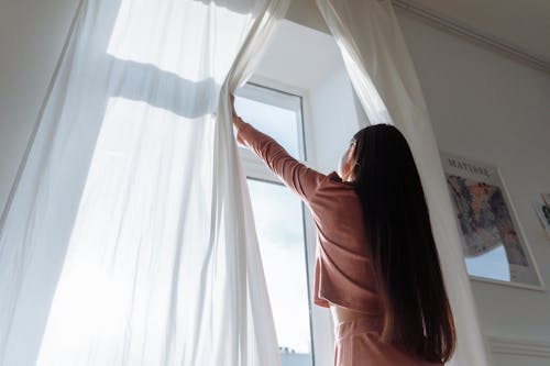 A Woman Opening a White Curtain