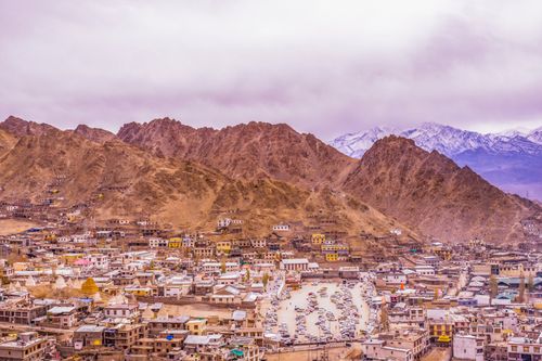 Free Colorful town surrounded by majestic mountains under overcast sky, showcasing breathtaking natural beauty. Stock Photo