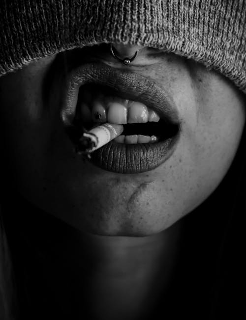 Grayscale Photo of a Person Smoking Cigarette