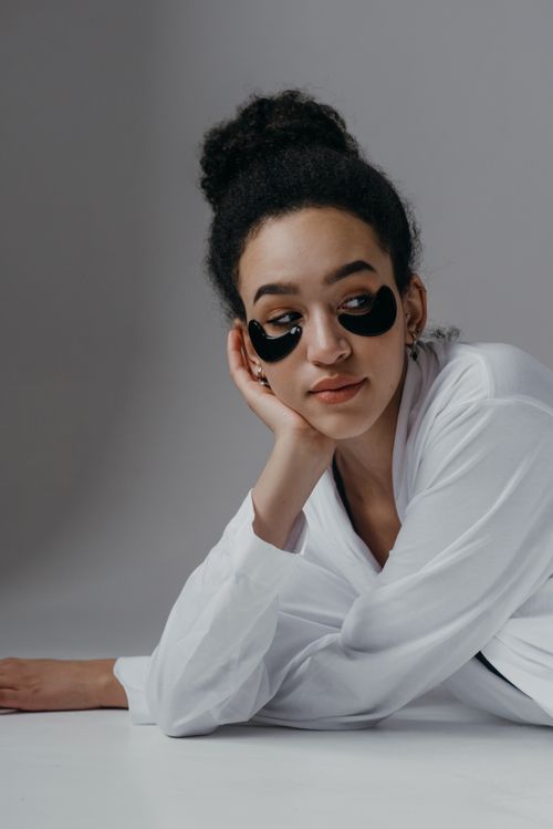 Free Woman in a white top using under eye masks, relaxing indoors. Skincare concept. Stock Photo