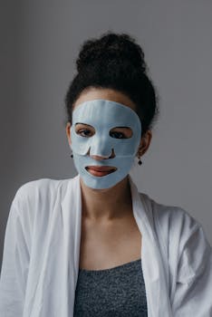 Close-up of a woman wearing a blue sheet face mask for a relaxing skincare routine indoors.