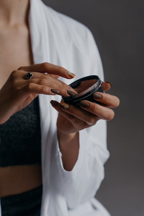 Woman Getting Cream on Black Container 