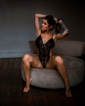 Stylish woman in black lingerie posing indoors, exuding confidence and elegance.