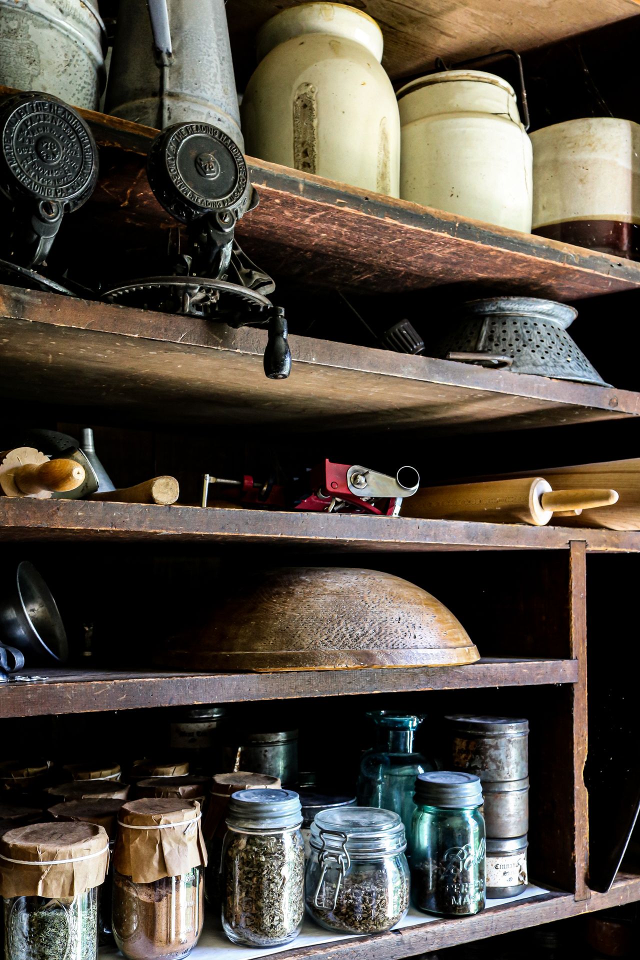 Rustic pantry shelves with vintage glass jars, crocks, and old kitchen tools