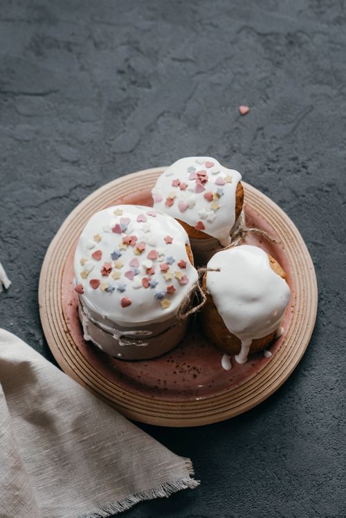 Free Delicious Easter cakes topped with white icing and colorful sprinkles on a plate. Stock Photo