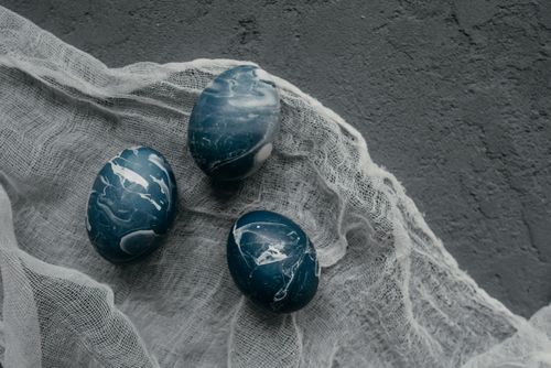 Free Three blue marble-patterned Easter eggs on textured fabric offer a unique artistic display. Stock Photo