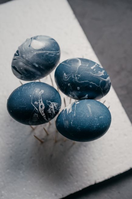 Elegantly marbled blue Easter eggs displayed on a minimal white surface.