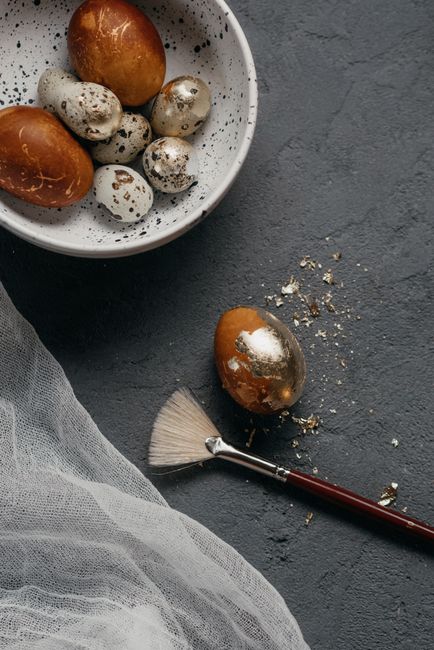 Still life of decorated Easter eggs with a brush on a gray textured surface.