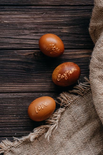 Decorative Easter eggs with inscriptions on a rustic wooden background, conveying a warm festive feel.