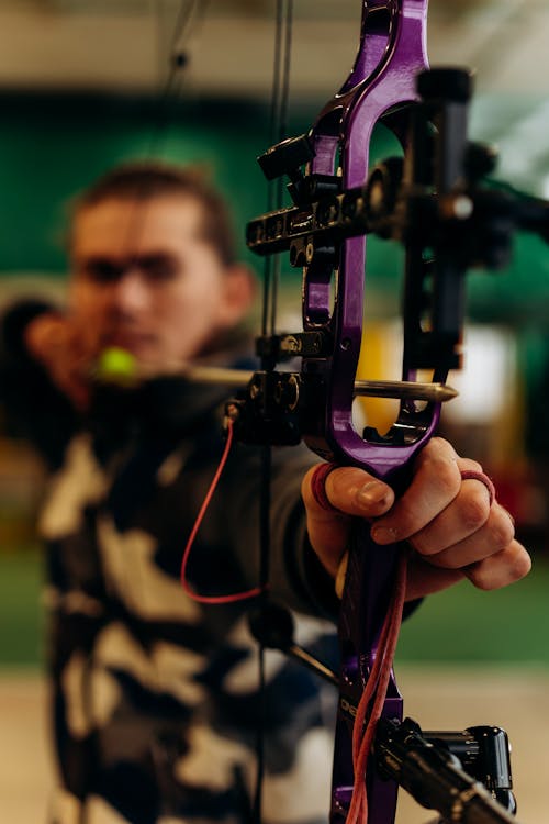 Free Man Aiming While Holding Purple Bow Stock Photo