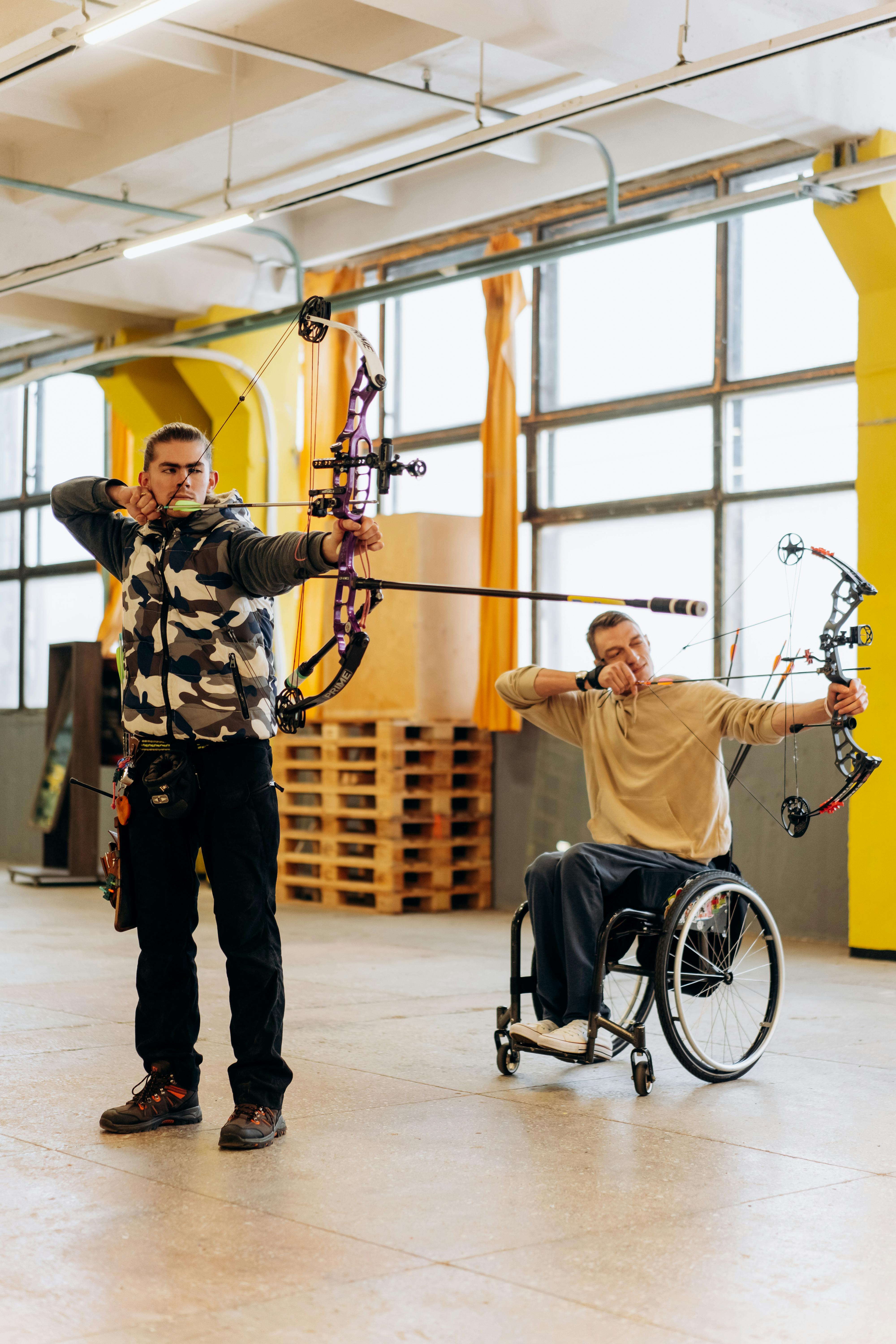 Man in White T-shirt and Black Pants Holding Black and Silver Bicycle