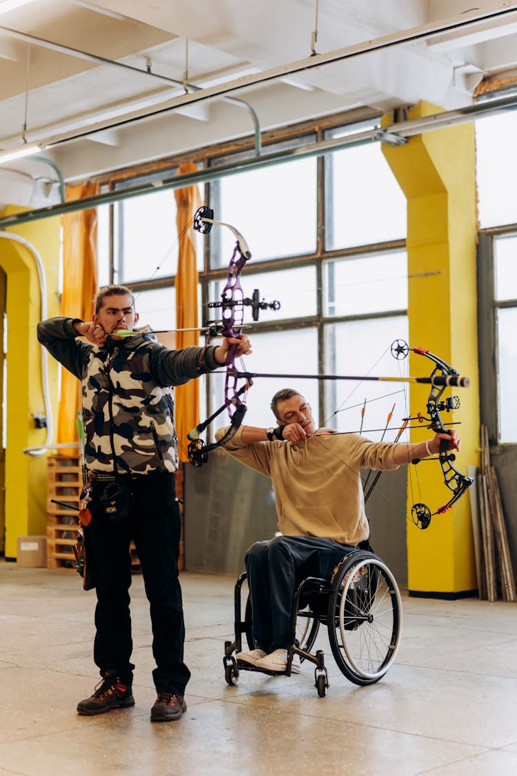 Man In Brown T-shirt And Black Pants Holding On Black Wheel Chair