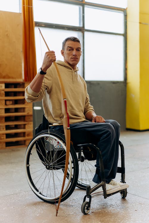 A Man in a Wheelchair Holding a Long Bow