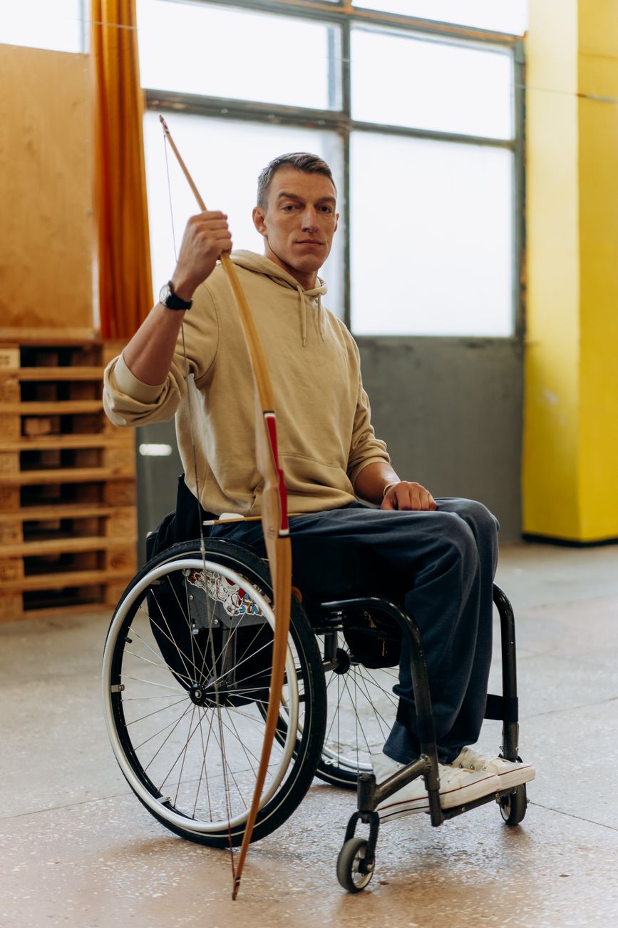 A Man in a Wheelchair Holding a Long Bow