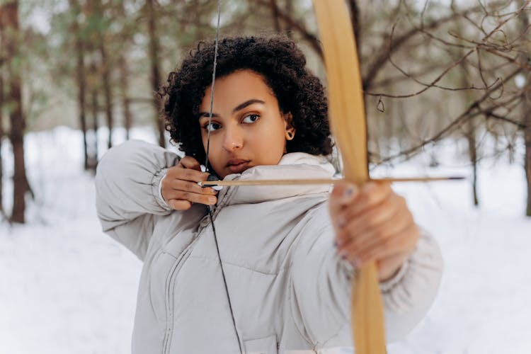 A Woman Holding A Bow And Arrow At The Forest