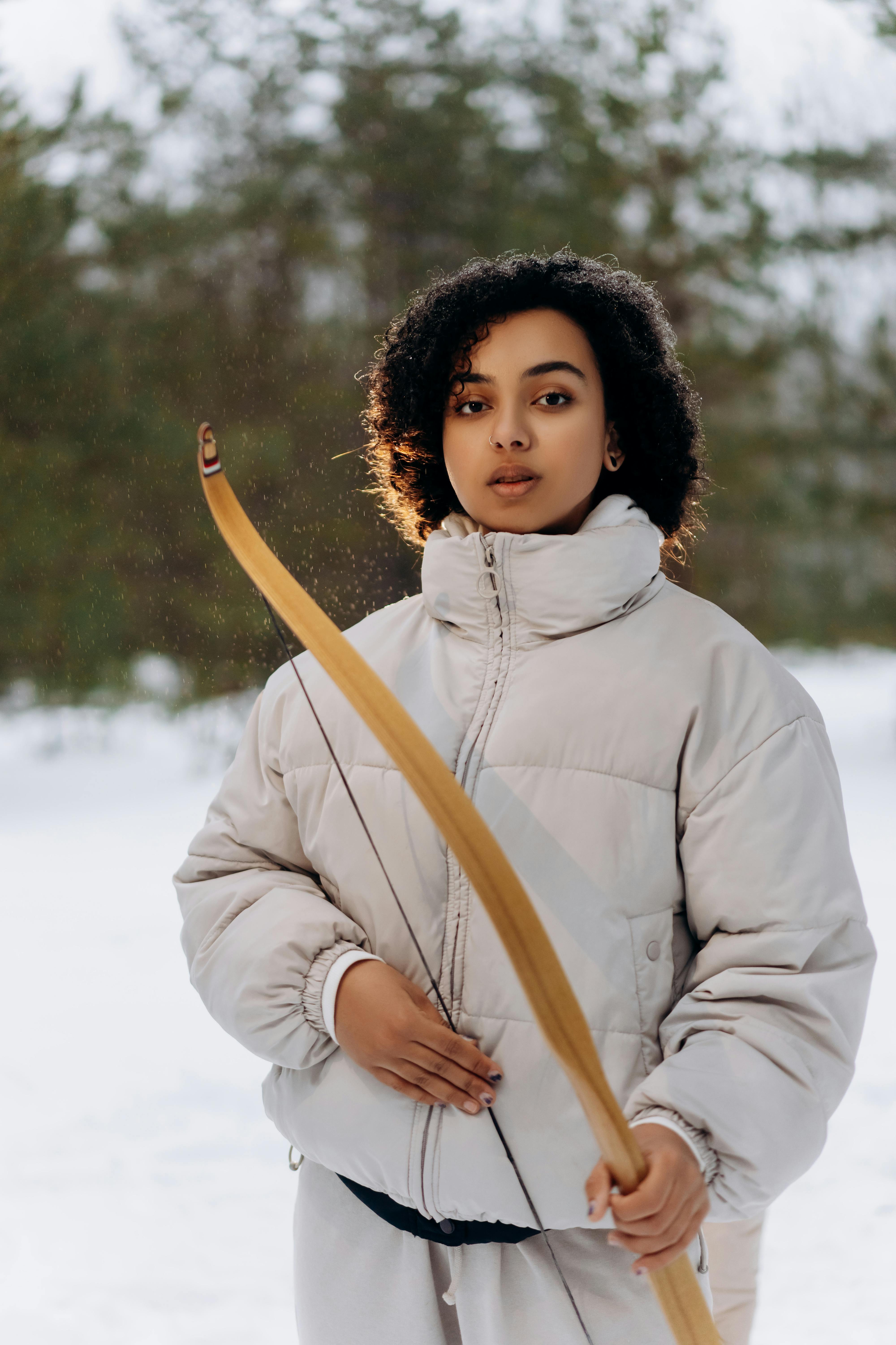 woman in white hoodie holding brown stick