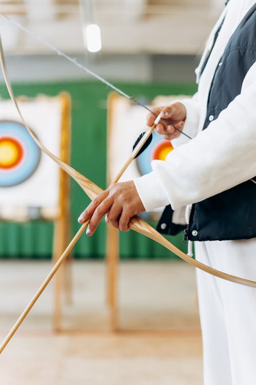 Person in White Long Sleeve Shirt Holding a Bow and Arrow