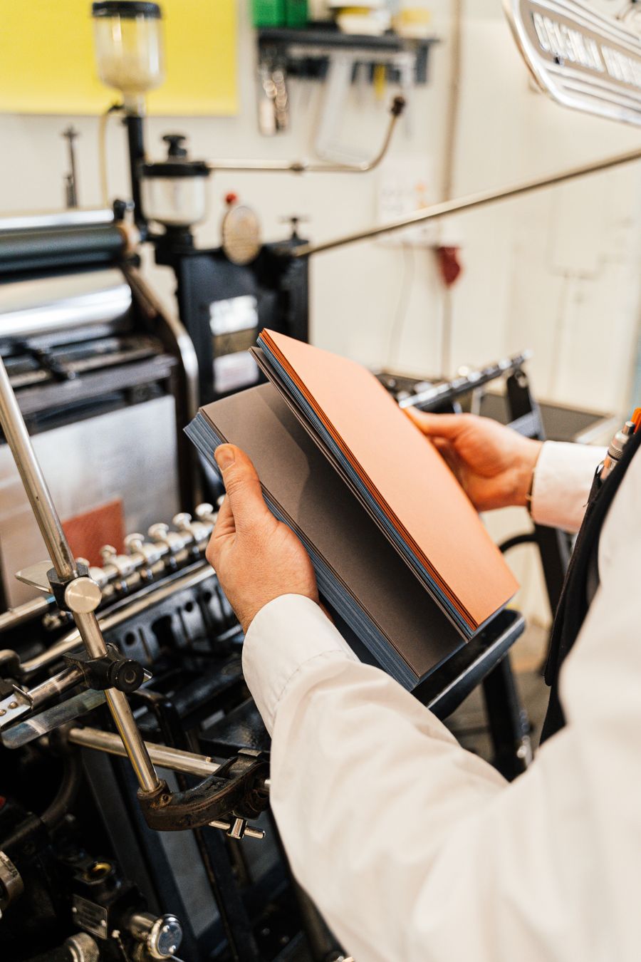 Hands holding freshly printed sheets at a printing press
