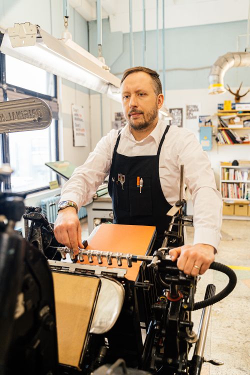Free Experienced craftsman using vintage printing press in a creative workshop. Stock Photo