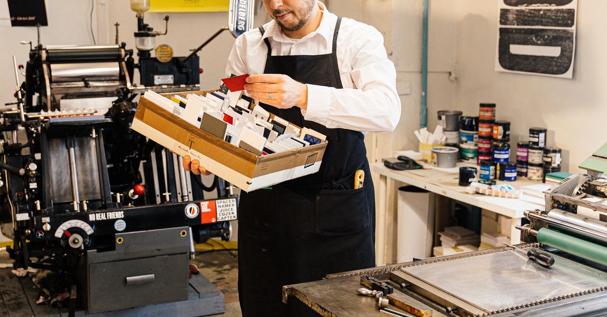 Adult man examining prints in an industrial workshop, highlighting craftsmanship.