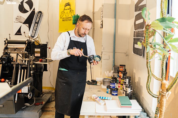 A Man Standing With A Can Of Paint