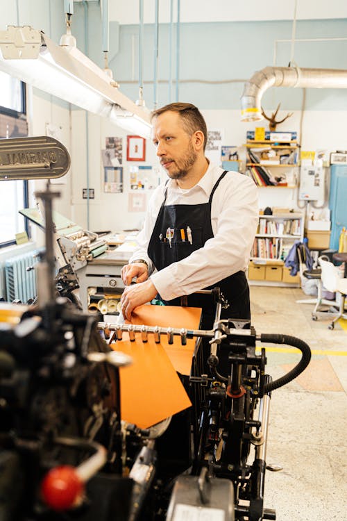 Man Using a Traditional Printing and Binding Machine in a Studio