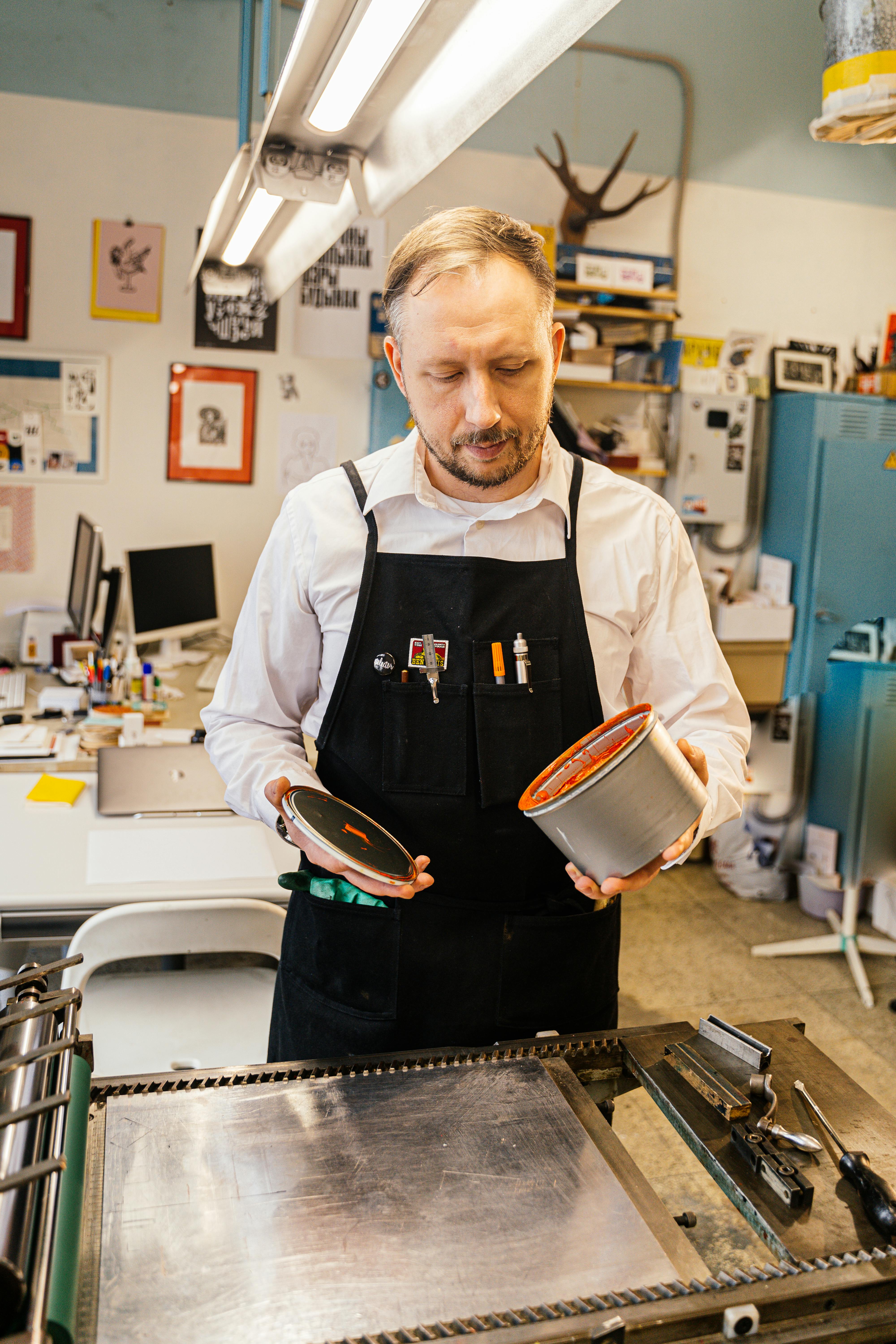 graphic designer in a studio with press opening a paint can